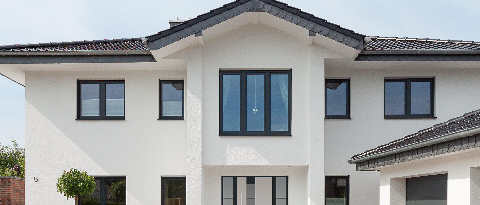 Fenster und Haustür mit schwarzem Rahmen im Neubau mit weißem Putz